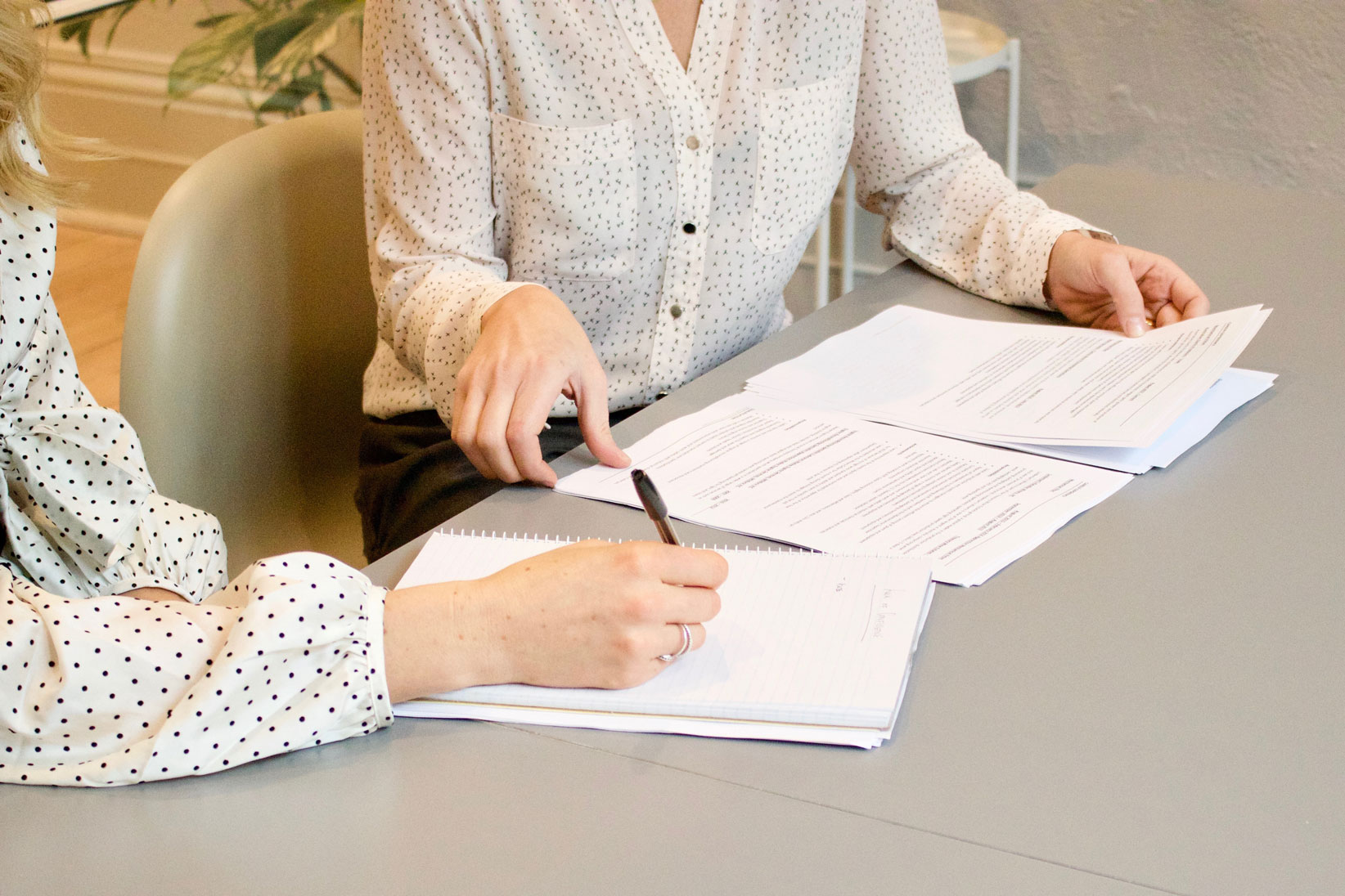 two woman working on paperwork, faces not visible